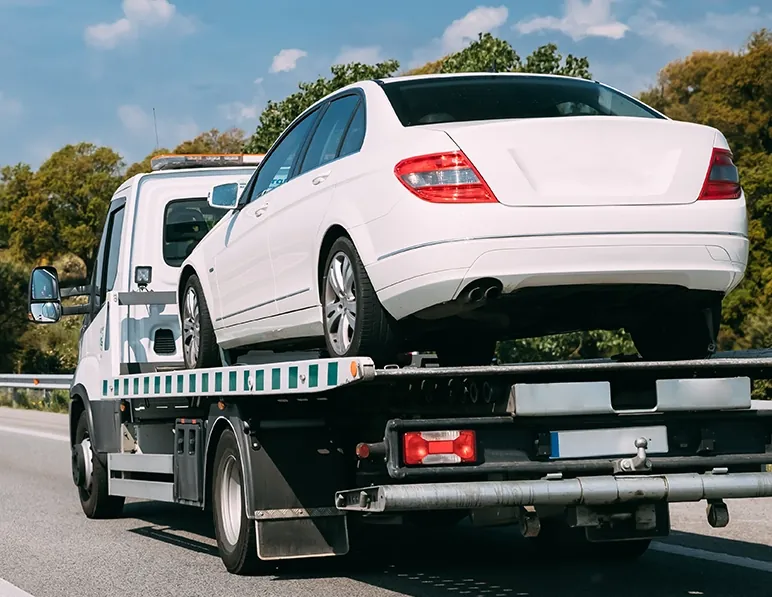 White sedan loaded on a flatbed for vehicle transport in Florida