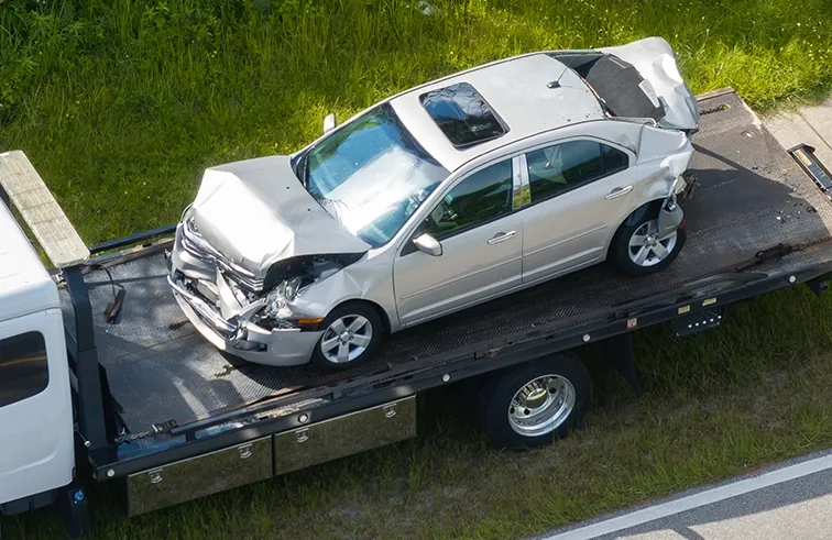 Damaged sedan secured on a flatbed tow truck in Tampa, FL